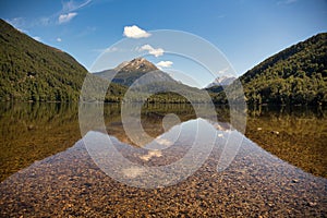 Isolated and remote Lake Sylvan surrounded by lush dense forest in Mt Aspiring national park near Glenorchy