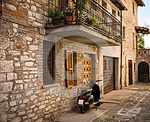 An isolated scooter parked in the courtyard of an old stone house of a medieval italian village Gubbio, Umbria, Italy