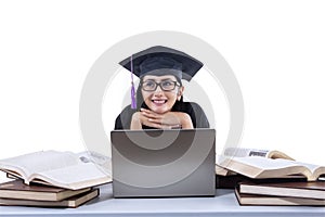 An isolated shot of happy female graduate study with laptop and books