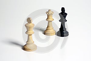 Isolated shot of two white and one black chess figures on a white background