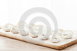 Isolated shot of the uncooked dumplings on a wooden platt
