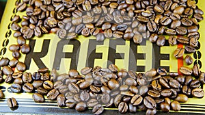 Isolated single word black coffee German: Kaffee on golden metallic  ground with roasted brown countless beans frame