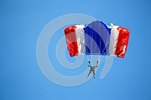Isolated skydiver in colorful parachute gliding after free fall