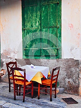 Small Cafe Table With Wicker Chairs and Green Wooden Shutters photo