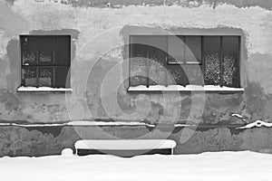 Isolated snowy bench under two windows