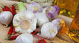 Isolated solo single clove garlic and fresh bulb on olive wood cutting board, chilis and oil glass bottles