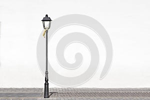 Isolated street light against a white wall on a cobblestone floor for fashion and urban background. No people and empty copy space