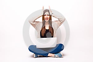 Isolated studio shot of a casually dressed young adult woman staring at her laptop