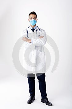 Isolated studio shot of male doctor wearing face mask while standing at white background