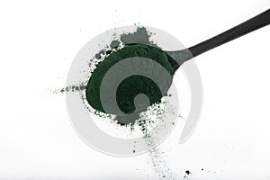 An isolated tablespoon of dried organic spirulina algae powder, on white or rustic background