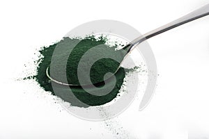 An isolated tablespoon of dried organic spirulina algae powder, on white or rustic background