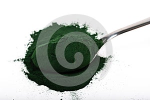 An isolated tablespoon of dried organic spirulina algae powder, on white or rustic background