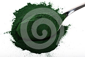 An isolated tablespoon of dried organic spirulina algae powder, on white or rustic background