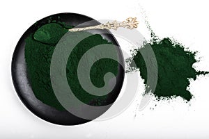An isolated tablespoon of dried organic spirulina algae powder, on white or rustic background