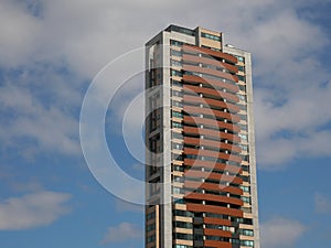 Isolated tall apartment building over a cloudy blue sky copy space