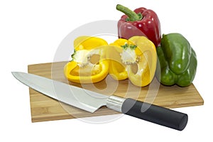 Isolated of three Bell peppers on wooden cutting board with kitchen knife