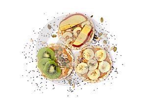Isolated three healthy rice cake meal with peanut butter, kiwi slice, banana, seeds and apple on white background