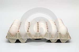 An isolated tray of eggs from recycled materials with 30 white eggs on a white background. Side view photo