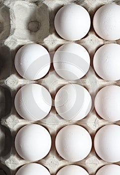 An isolated tray of eggs from recycled materials with white eggs on a white background. Top view photo