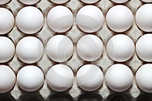 An isolated tray of eggs from recycled materials with white eggs on a white background. Top view photo