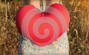 Isolated two hands gently raise and hold red heart with love and respect with background of nature