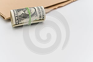 Isolated US dollar banknotes roll on a white and brown paper background with copy space