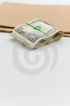 Isolated US dollar banknotes wad on a white and brown paper background with copy space