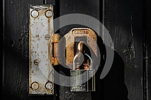 Isolated view of an old, rusting metal shackle and lock.