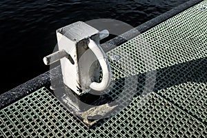 Isolated view of a painted mooring post seen on a man-made jetty, seen at the waters edge.