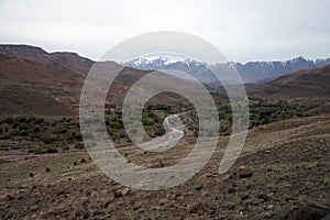 Isolated village overlooking valley, with snow capped mountains in background