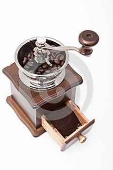 Isolated vintage coffee bean grinder and fresh ground coffee