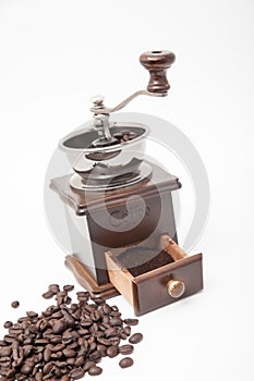 Isolated vintage coffee bean grinder and fresh ground coffee