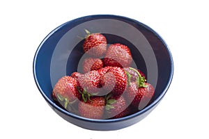 Isolated on white background blue bowl with ripe red strawberries close-up