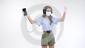 Isolated white background. girl in gloves and a mask in headphones is dancing