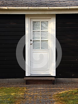 Isolated White Door on Black Wooden House