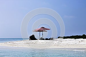 Isolated woman sleeping under two pink beach umbrellas on the maldivian sand Ari Atoll, Maldives,Asia