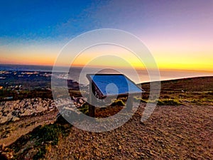 Isolated wooden board on a grassy hilltop overlooking a sun-kissed ocean view in Portugal