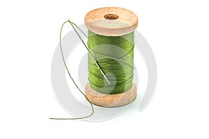 Isolated wooden spool of green thread and needle