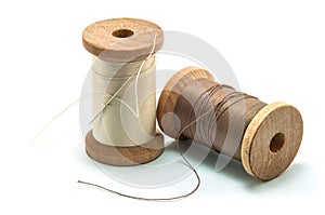 Isolated wooden spool of thread and needle