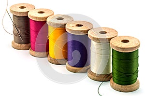 Isolated wooden spools of thread with a needle