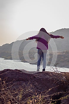 isolated young girl at mountain top with lake view backbit shot from flat angle