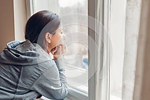 Isolation at home during coronavirus covid-19 pandemic. Woman looking at window. Stay safe at home on quarantine