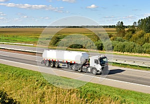 Isothermal Tank truck driving on highway. Oil and Gas Transportation and Logistics. Metal chrome cistern tanker with