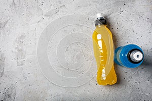 Isotonic energy drink. Bottles with blue and yellow transparent liquid, sport beverage on a concrete background