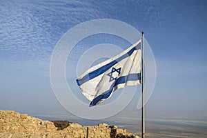 Israel flag on blue sky with ruin of Masada