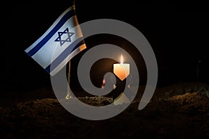 Israel flag on burning dark background with candle. Attack on Israel, mourning for victims concept or Concept of crisis of war and