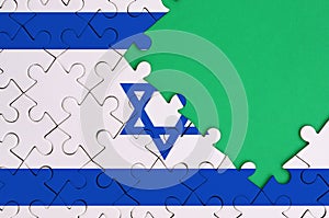 Israel flag is depicted on a completed jigsaw puzzle with free green copy space on the right side
