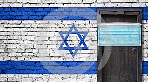 Israel flag painted on brick wall and closed door with medical mask protected