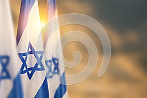 Israel flags with a star of David over cloudy sky background on sunset. Banner with place for text.