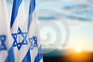 Israel flags with a star of David over cloudy sky background on sunset. Banner with place for text.